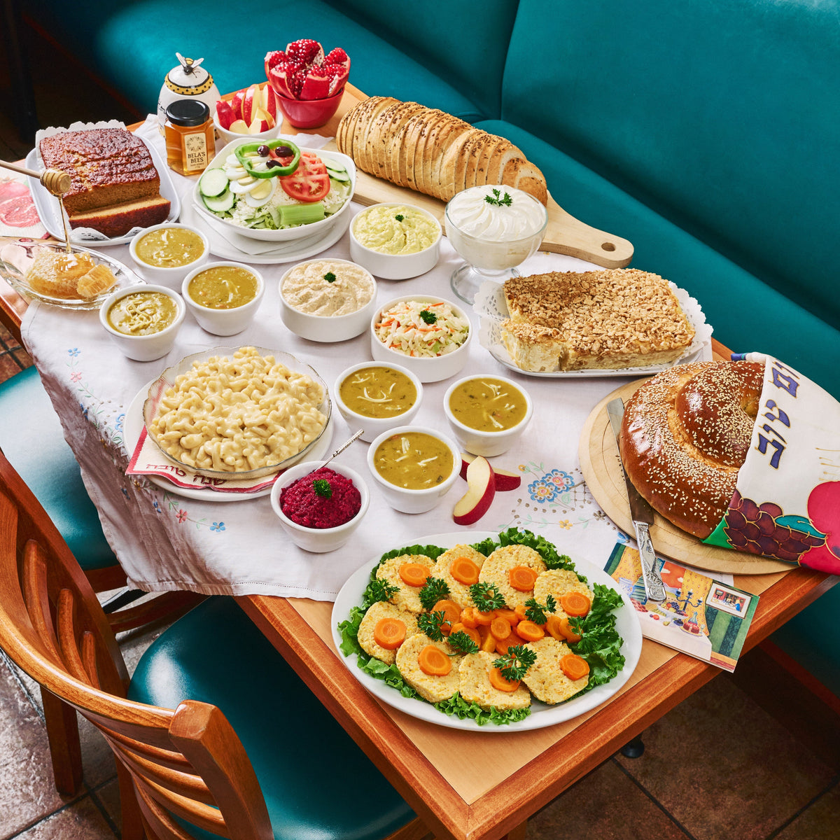 Diner table with various food items including sandwiches, salads, and side dishes on a checkered tablecloth. For Rosh Hashanah Toronto with Gefilte Fish
